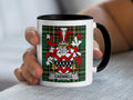 White mug with black rim featuring the Cadwell family crest on a tartan background.