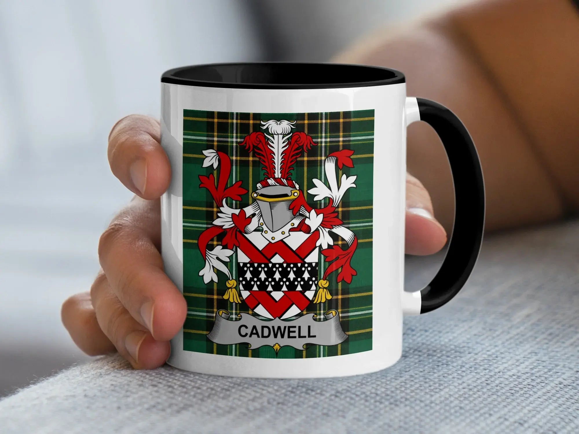 White mug with black rim featuring the Cadwell family crest on a tartan background.