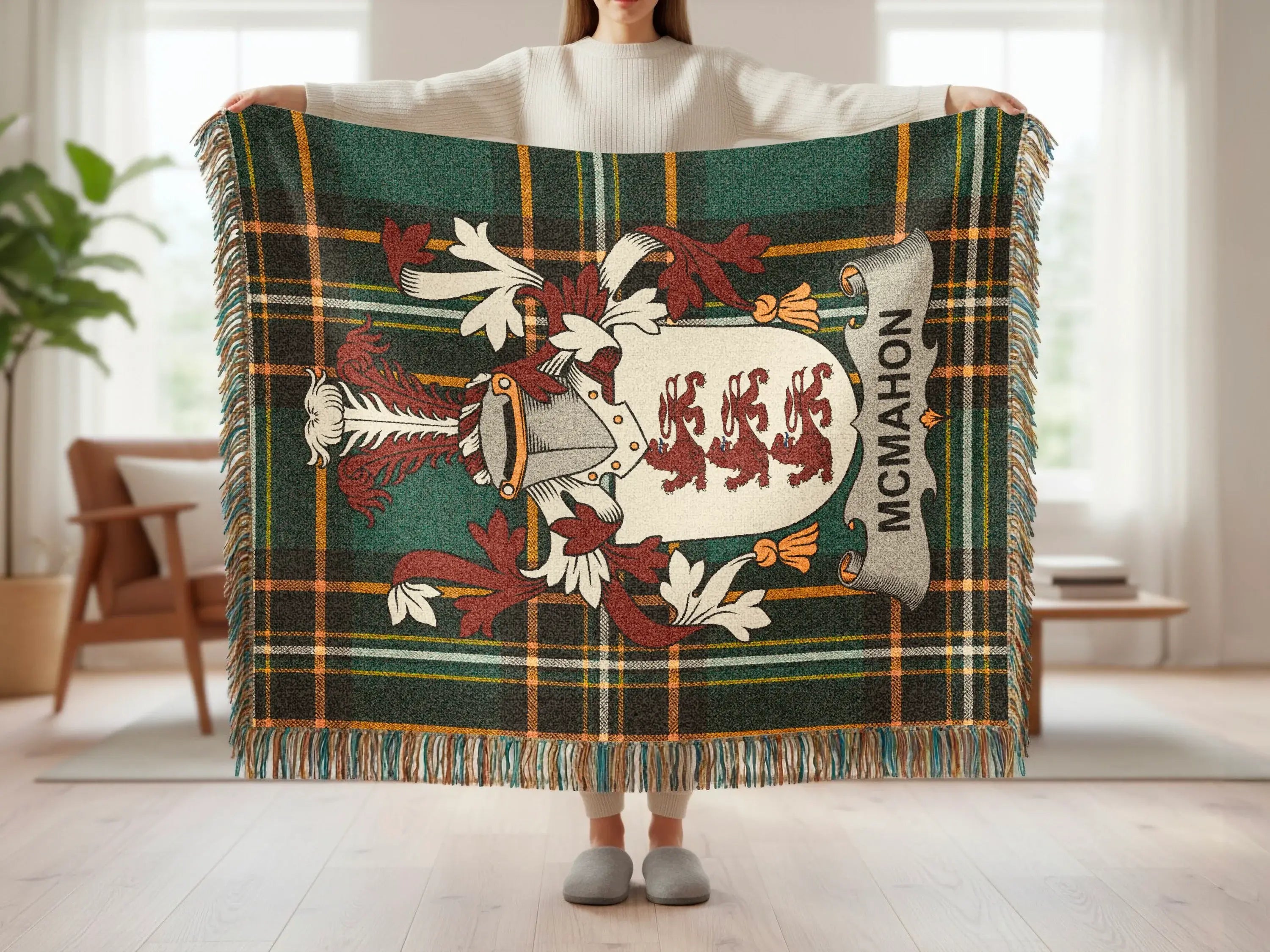 McMahon tartan blanket with crest and fringe, held by person.