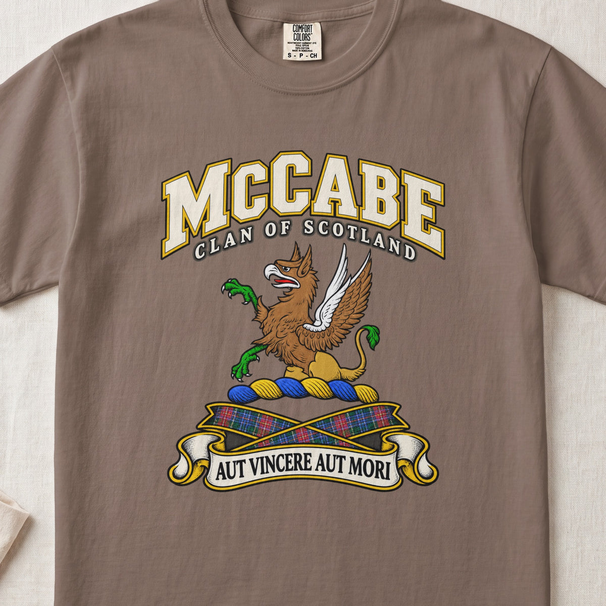 McCabe Scottish clan T-shirt in Espresso, front view with a brown and gold winged griffin with green claws and motto banner.