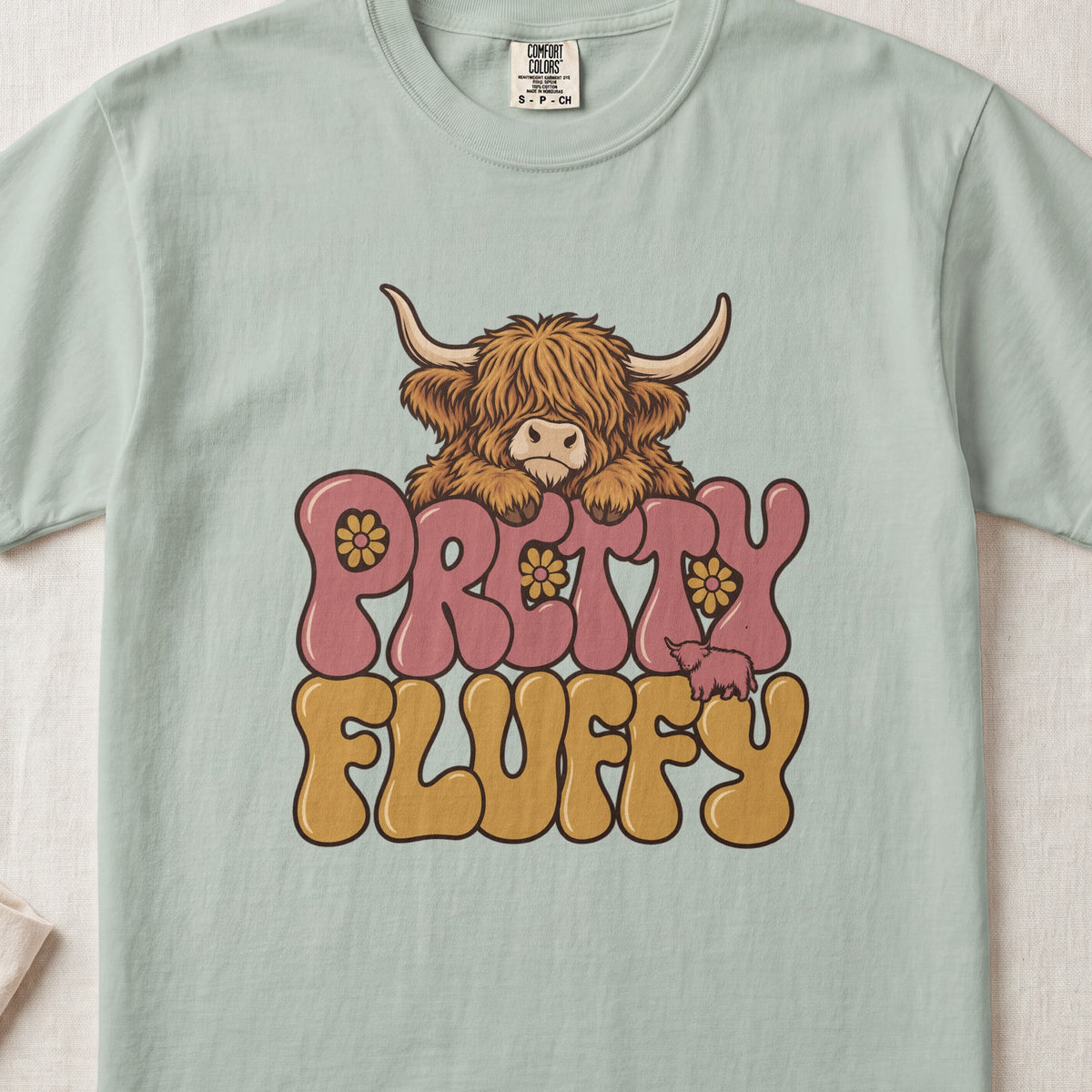 Pretty Fluffy Highland cow design on a Bay Comfort Colors 1717 T-shirt, flat lay