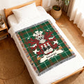 Green plaid blanket with George crest and family name on a bed.