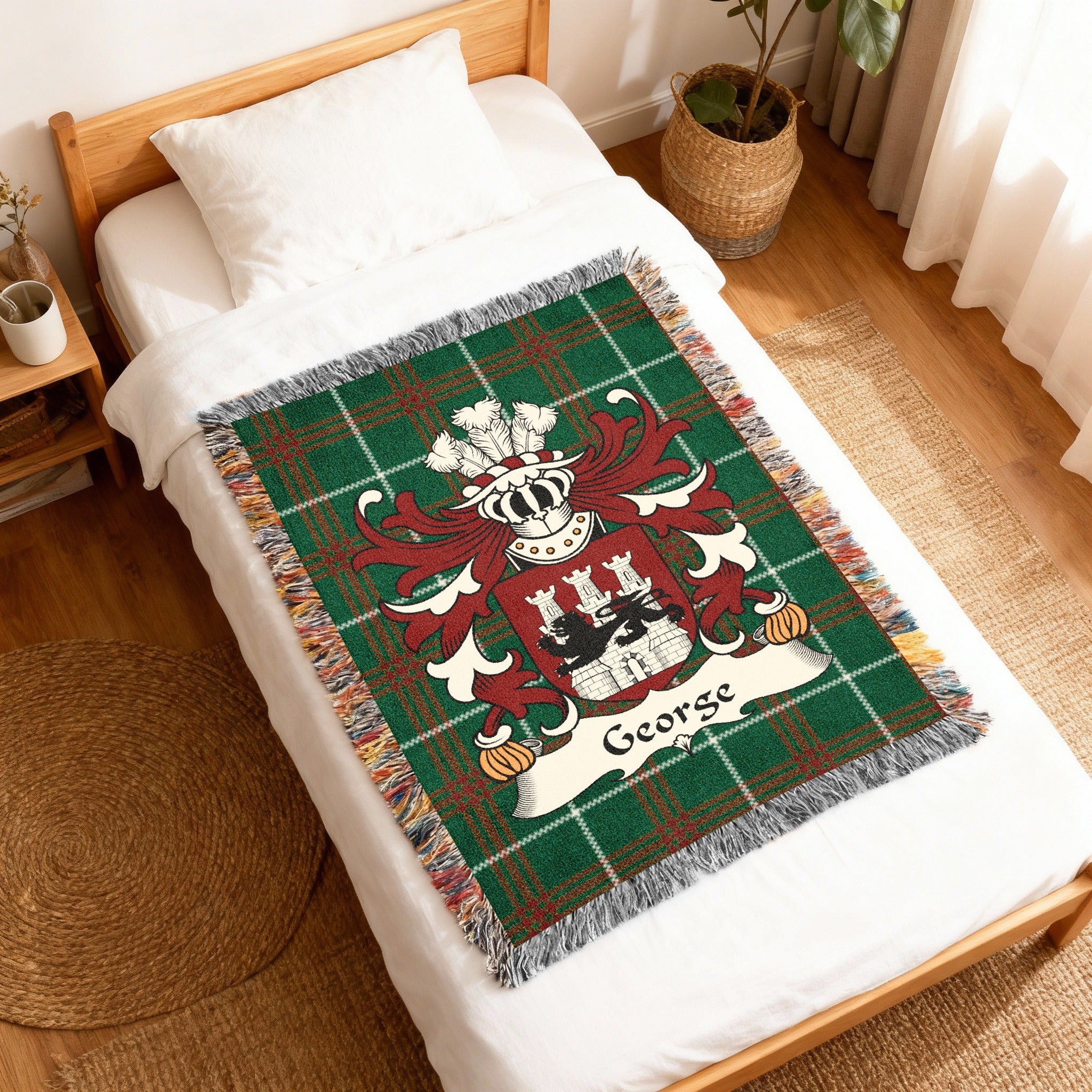 Green plaid blanket with George crest and family name on a bed.