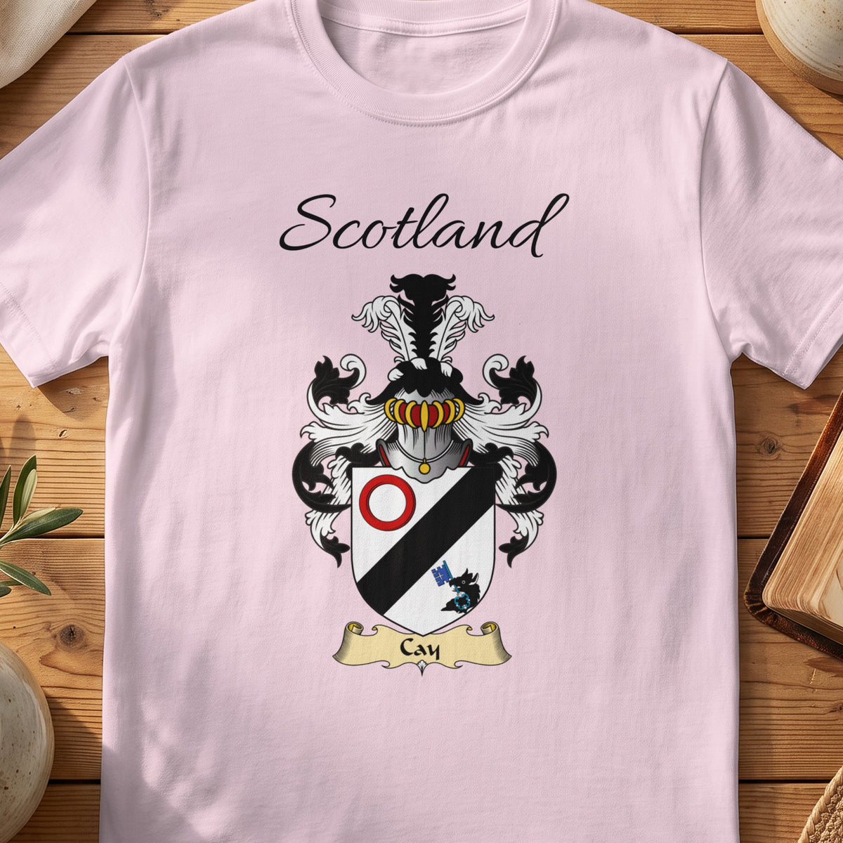 Light Pink Cay Scottish family shield T-shirt featuring a black diagonal band with a red ring