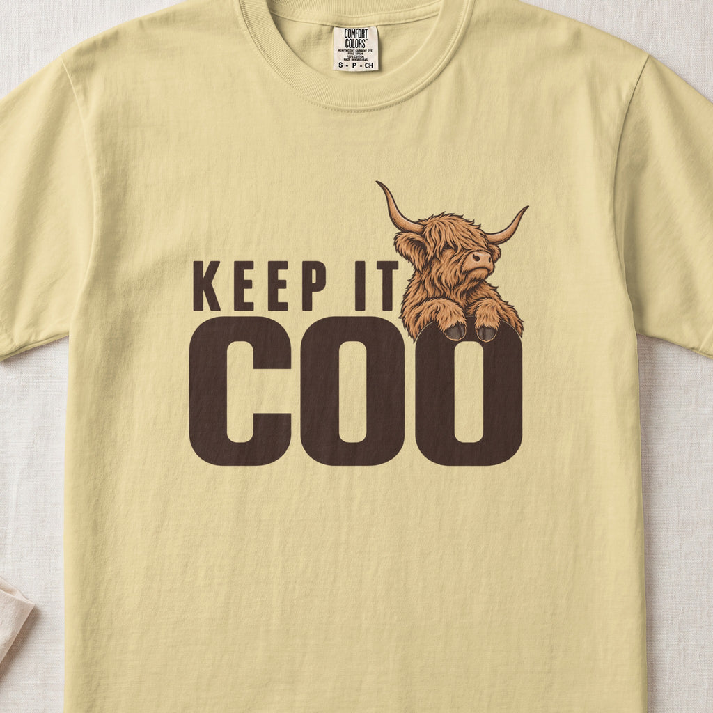 Keep It Coo Highland cow design on a Butter Comfort Colors 1717 T-shirt, flat lay