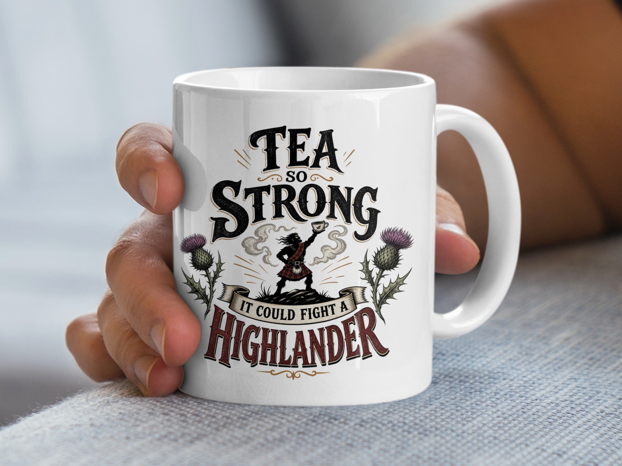 White mug with "Tea so strong it could fight a Highlander" text and Scottish imagery.