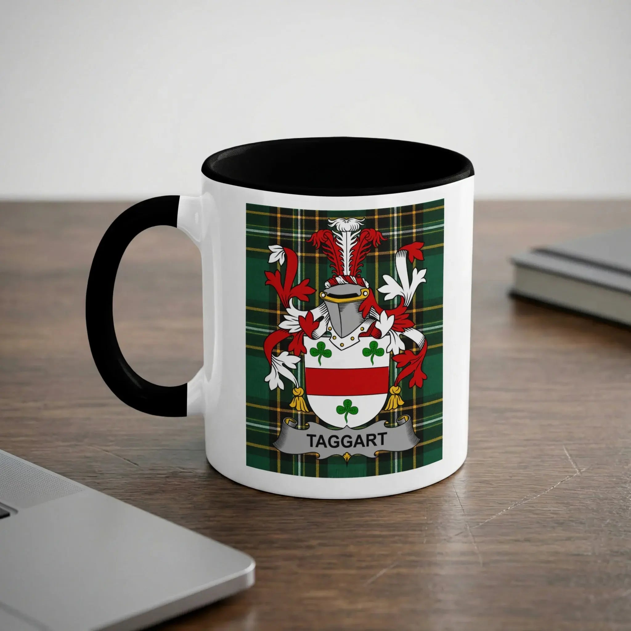 White mug with black handle featuring Taggart family crest on a tartan background.