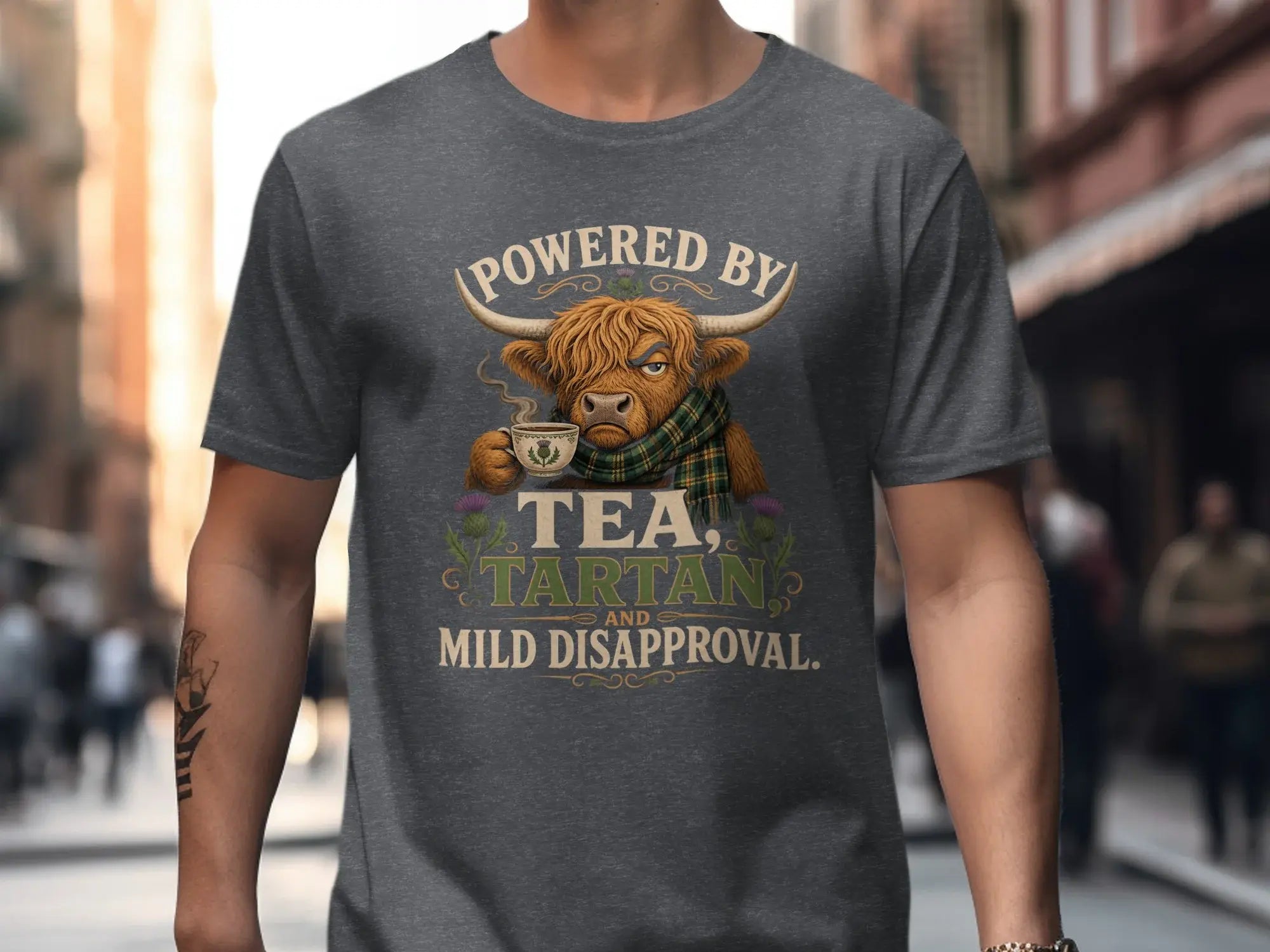 Highlander bull wearing a tartan scarf, holding a teacup, with text "POWERED BY TARTAN AND MILD DISAPPROVAL."