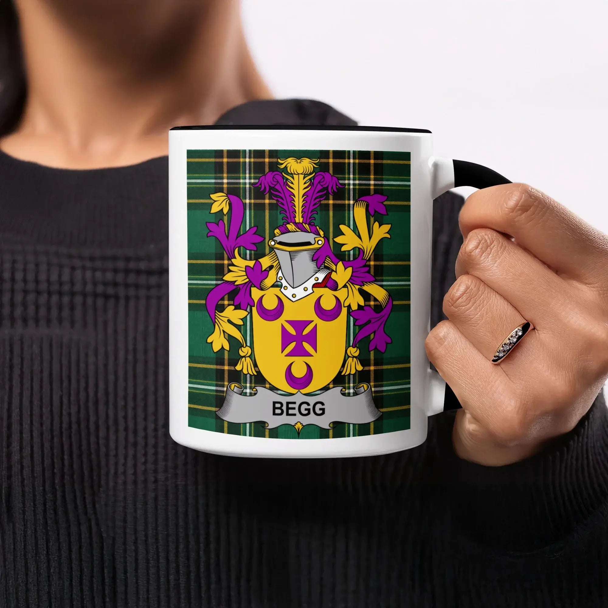 White mug with black handle displaying a coat of arms on green tartan.