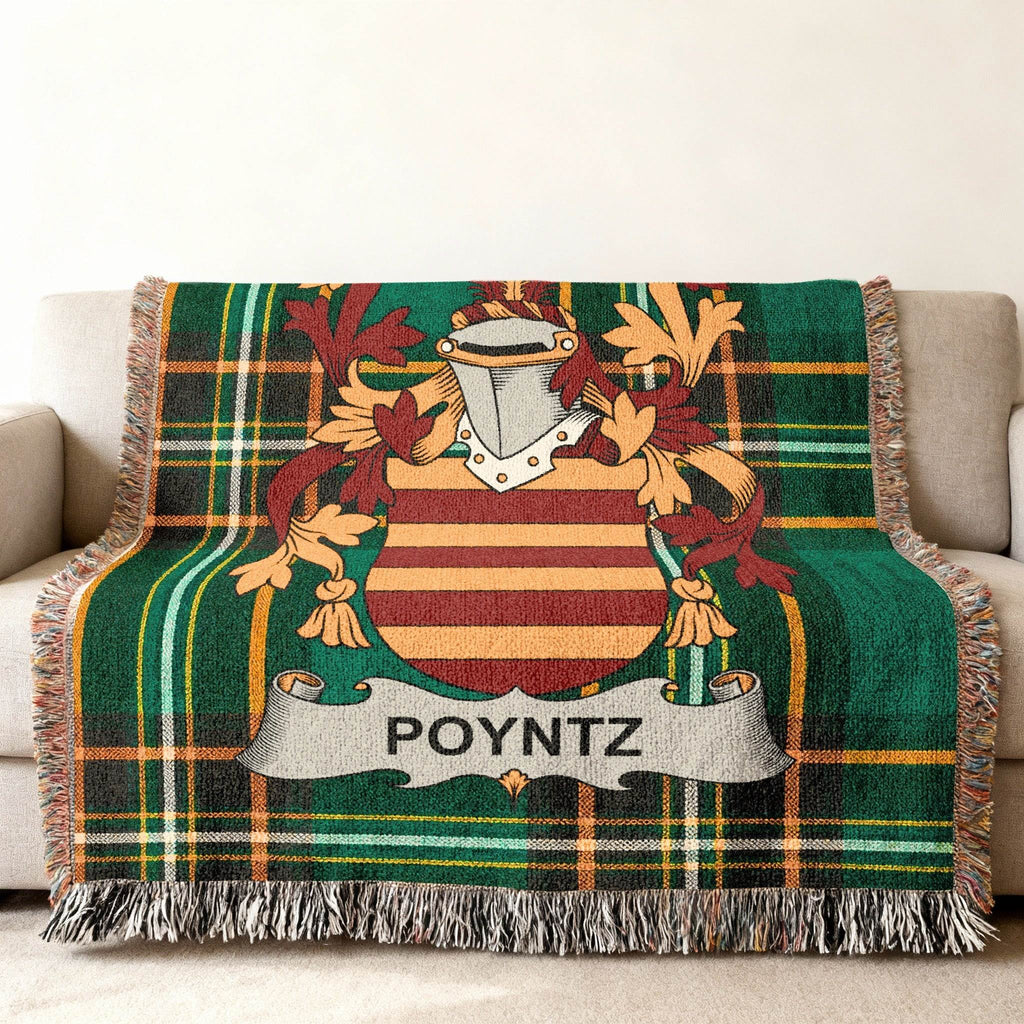 Green plaid throw blanket with Poyntz family crest on couch.