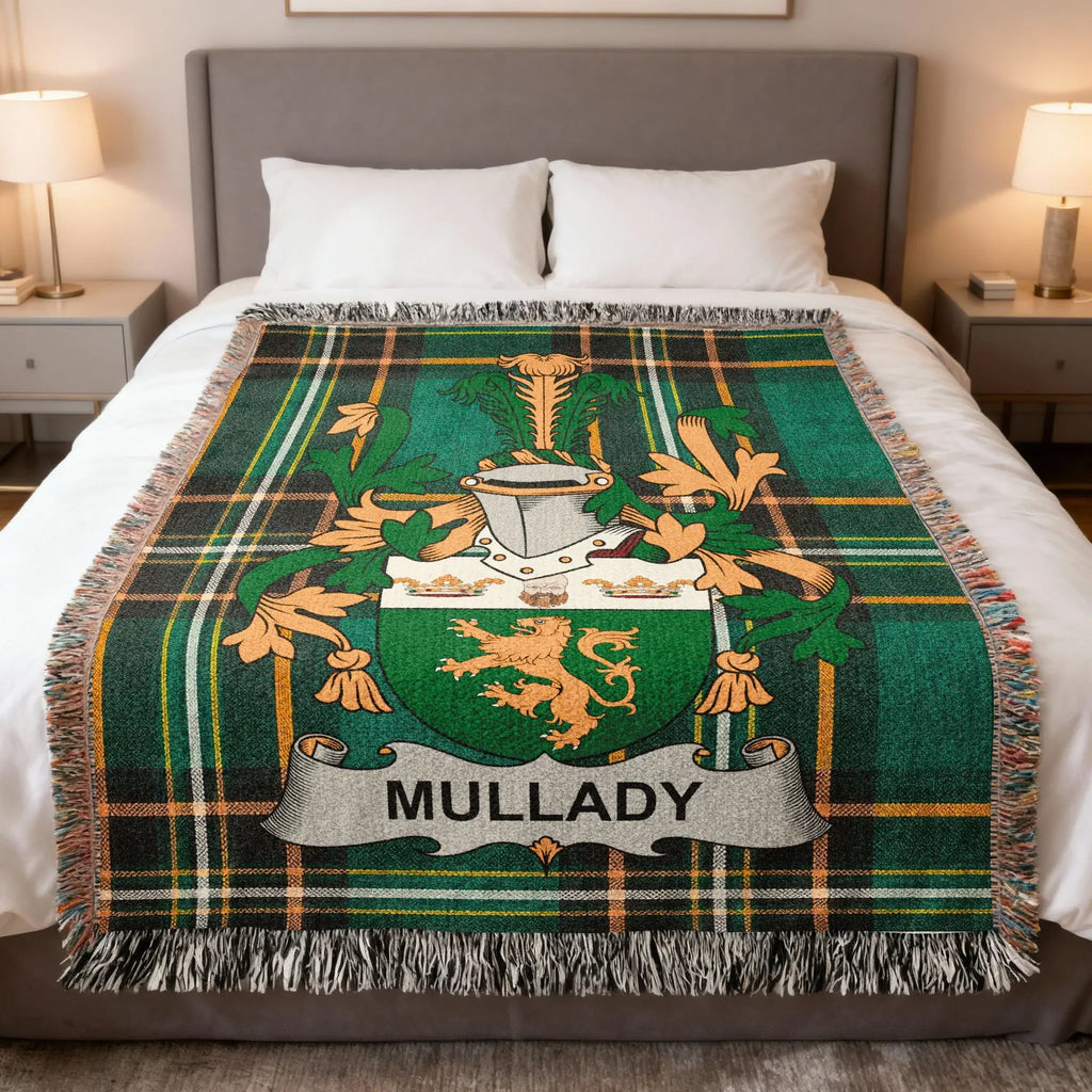 Green tartan blanket with Mullady family crest and fringe on a bed.