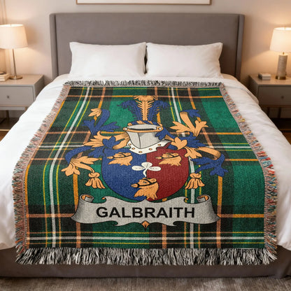 Galbraith family crest on a green tartan plaid blanket on a bed.