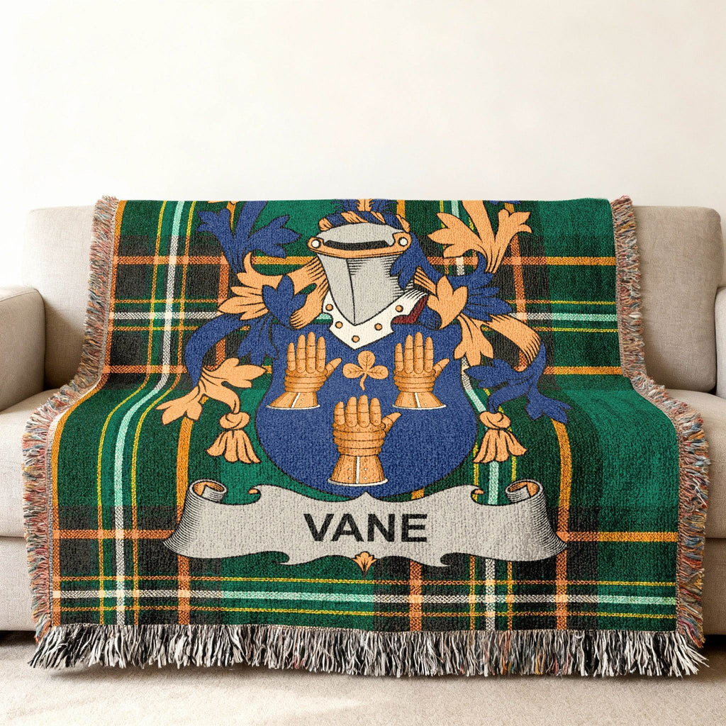 Woven blanket with plaid pattern and Vane family crest in blue, gold, and green.