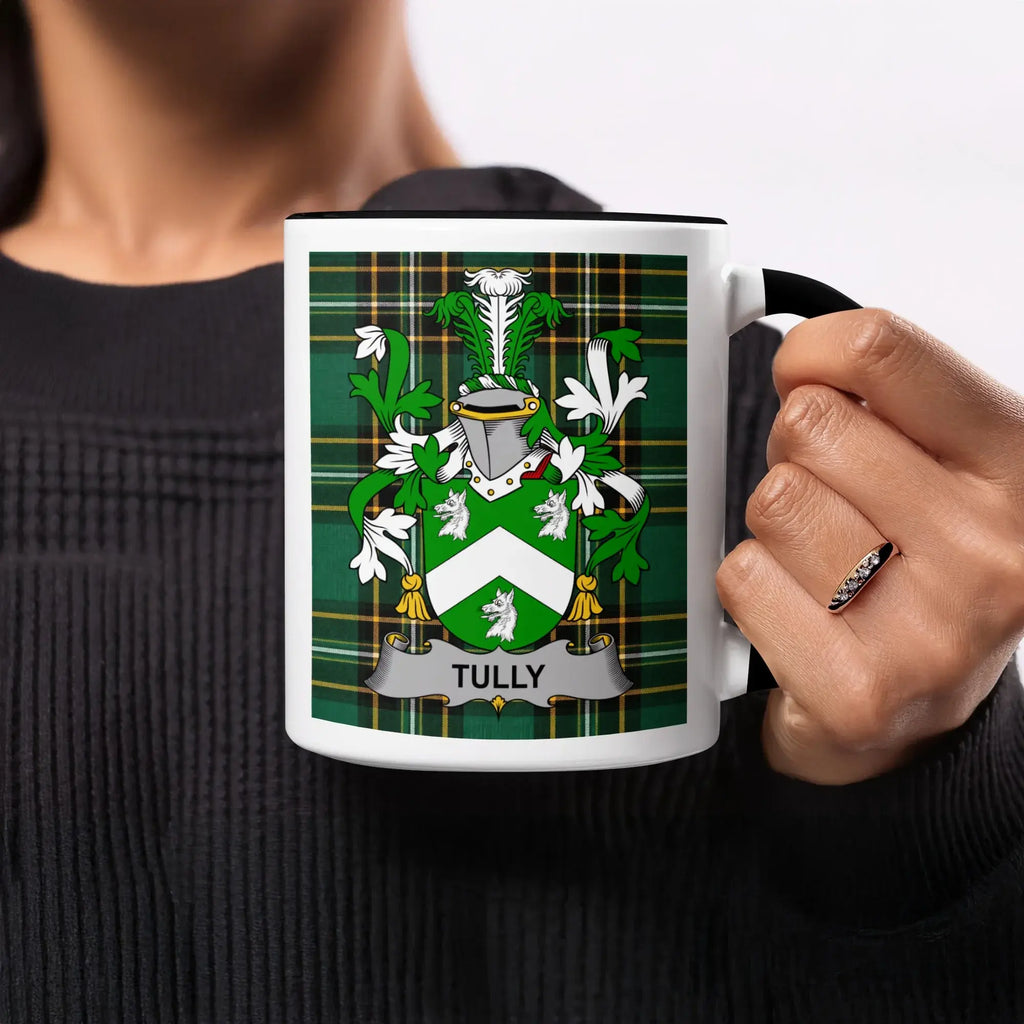 Tully family crest on a green plaid mug held by a person.