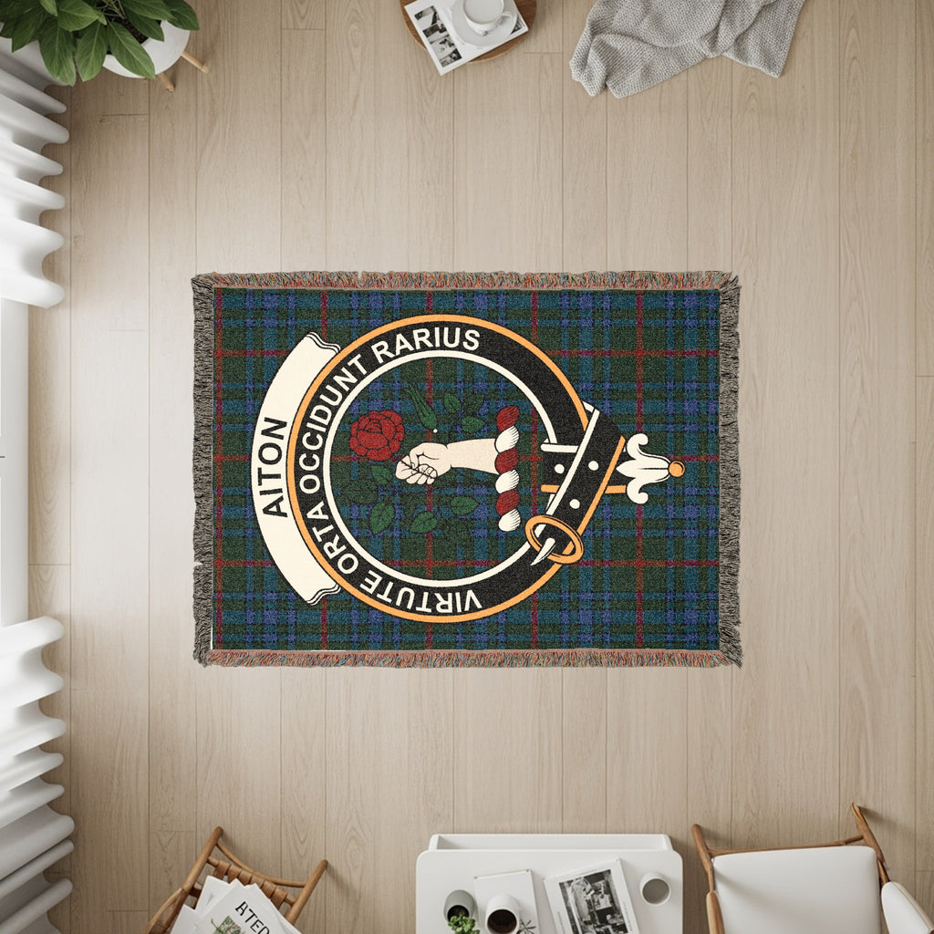 Aiton woven blanket displayed on a wall, featuring the crest badge and tartan background