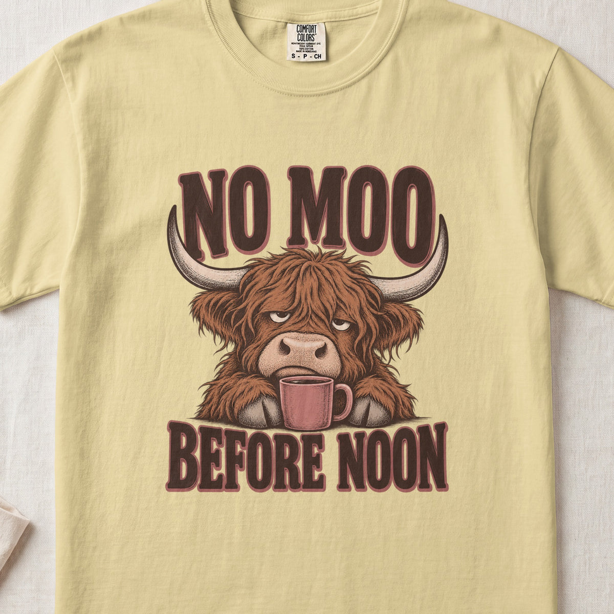 No Moo Before Noon Highland cow design on a Butter Comfort Colors 1717 T-shirt, flat lay