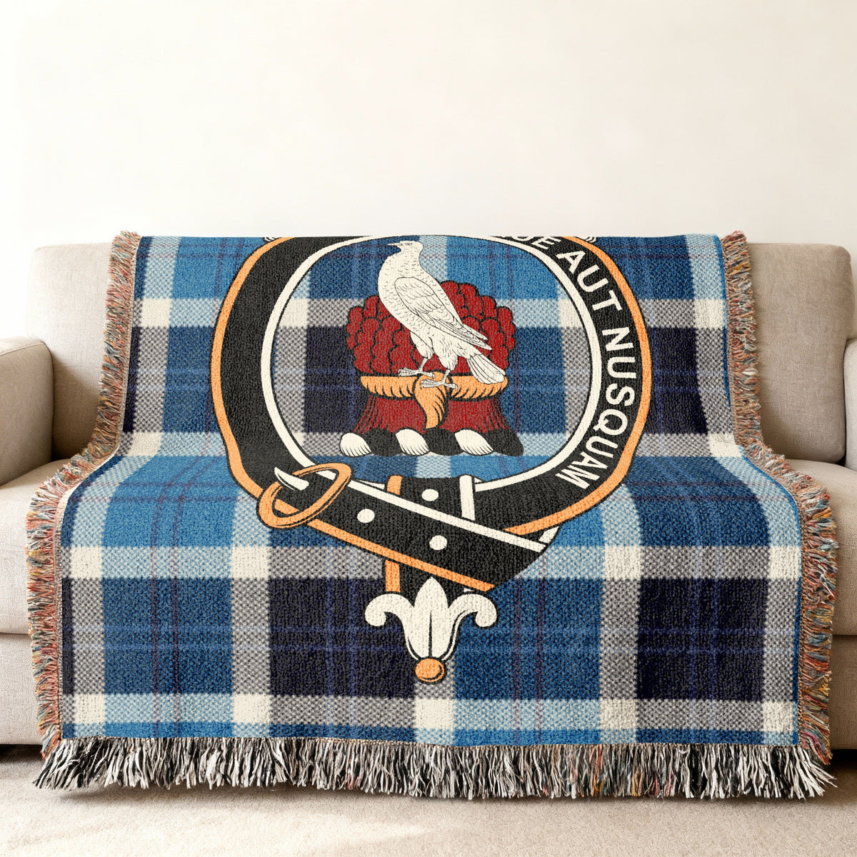 Close view of the Whitefoord woven blanket draped over a sofa, showing the crest and fringed edges