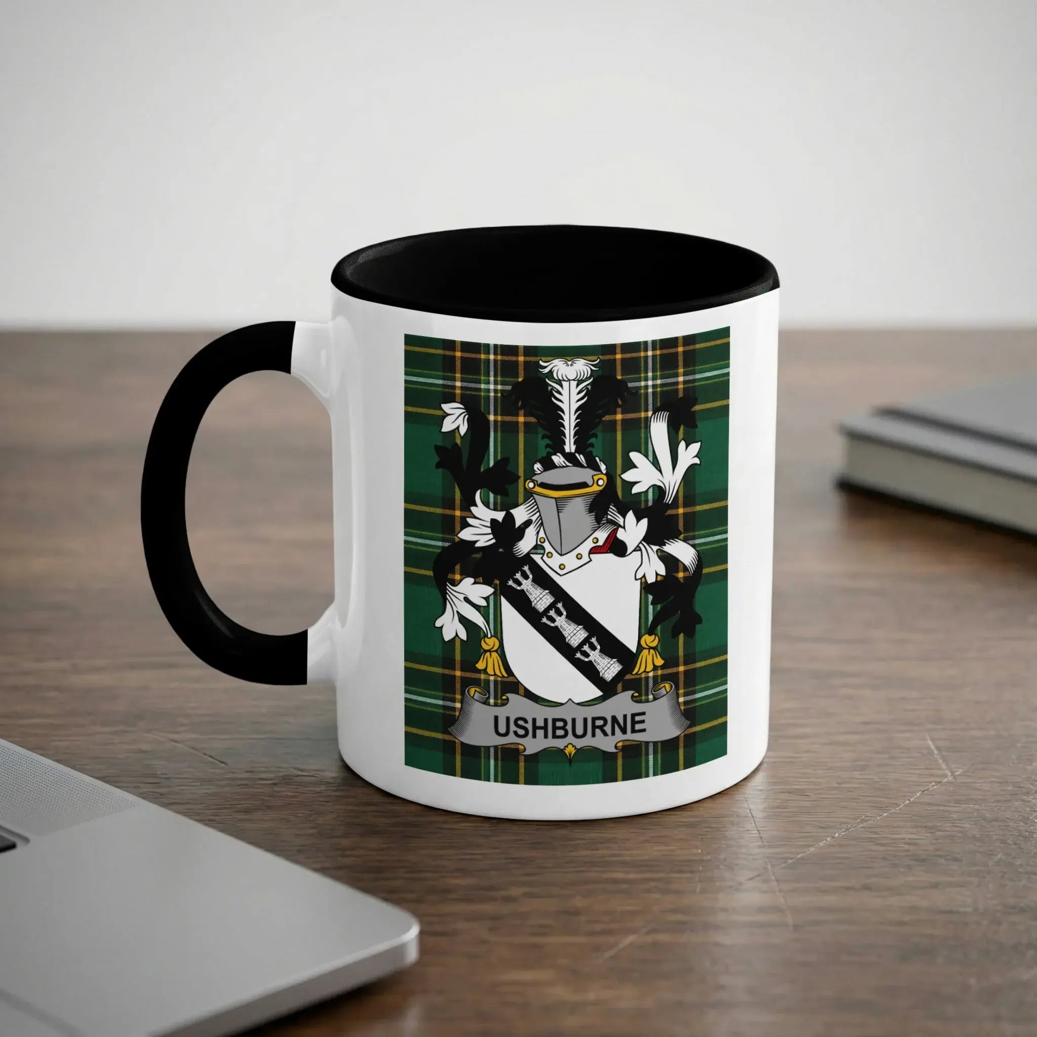 White mug with black handle featuring the Ushburne coat of arms on a green plaid background.