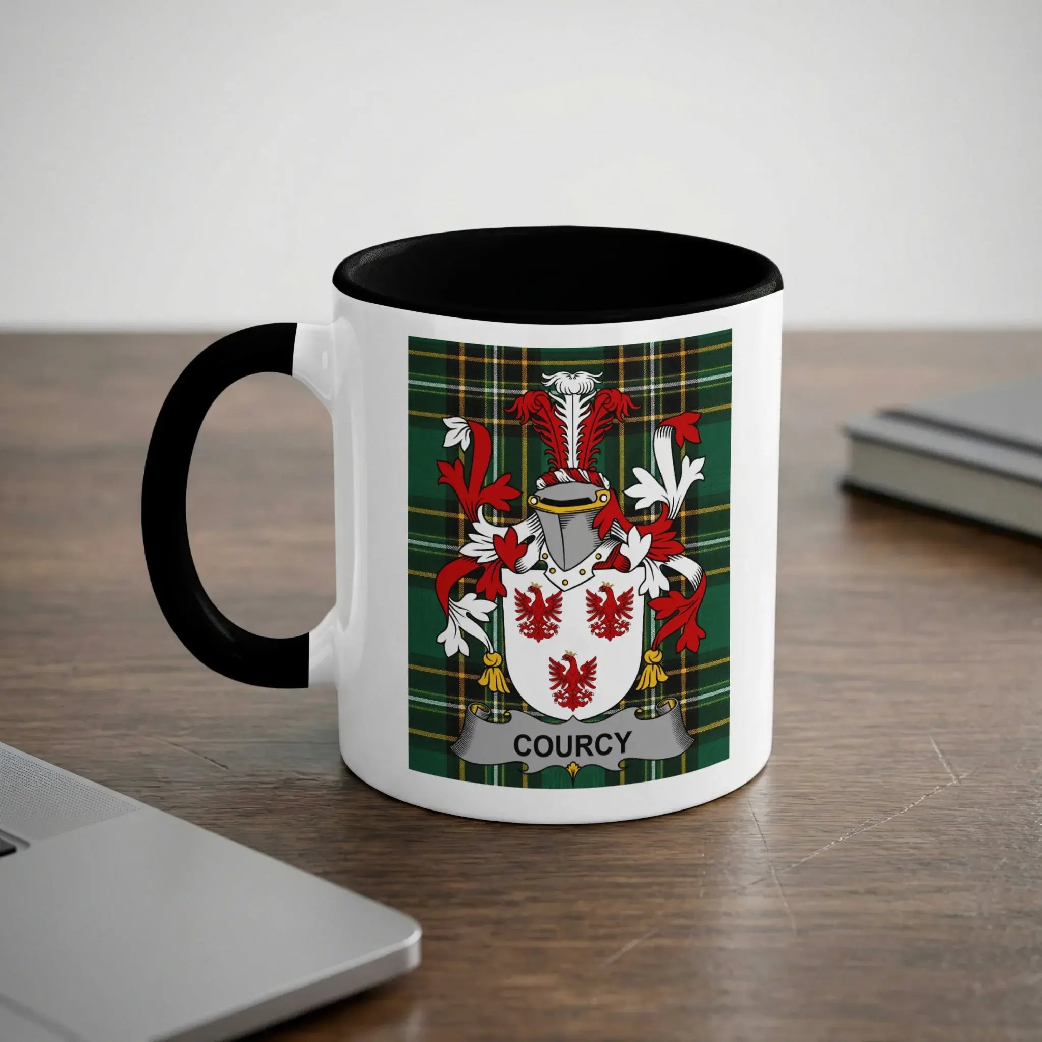 White mug with black handle and rim, featuring a Courcy family crest.