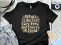 Black t-shirt with "Wha's Like Us? Gey Few, and They're A' Deid" text.