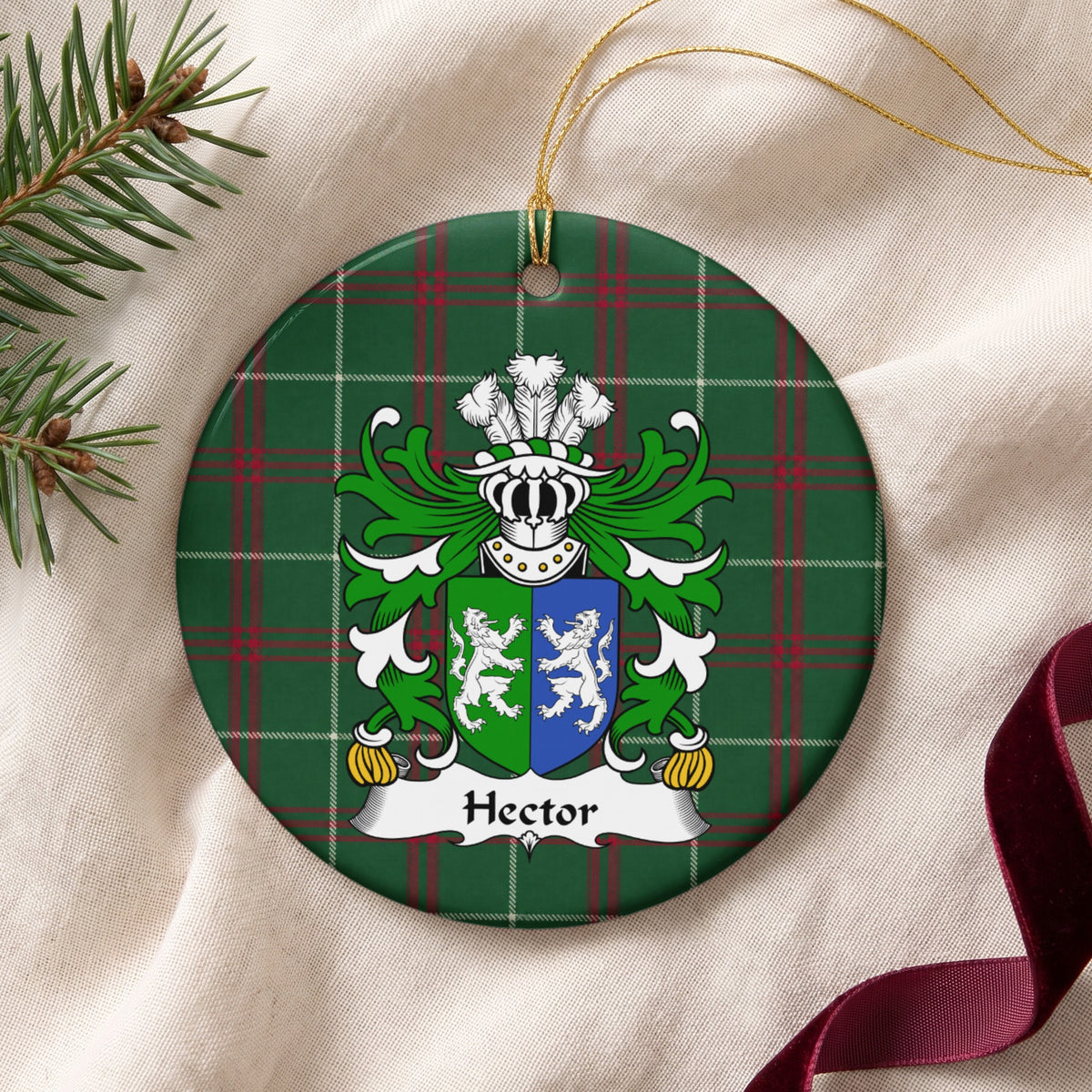 Hector ornament on cream fabric beside evergreen and burgundy ribbon, with gold string; two facing white lions on a green-and-blue divided shield.