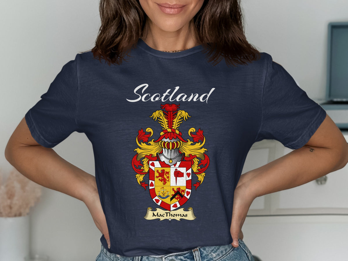 Model wearing a navy MacThomas T-shirt featuring a quartered red-and-gold shield with a decorative border