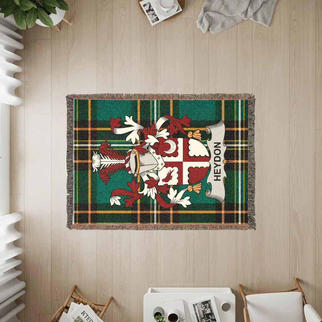 Woven blanket with the HEYDON family crest on a green plaid background.