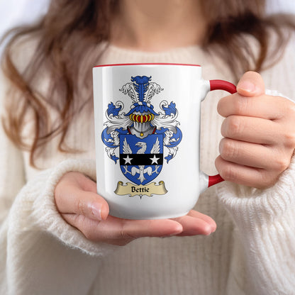 Mug with Bettie surname crest and red handle held by a person.