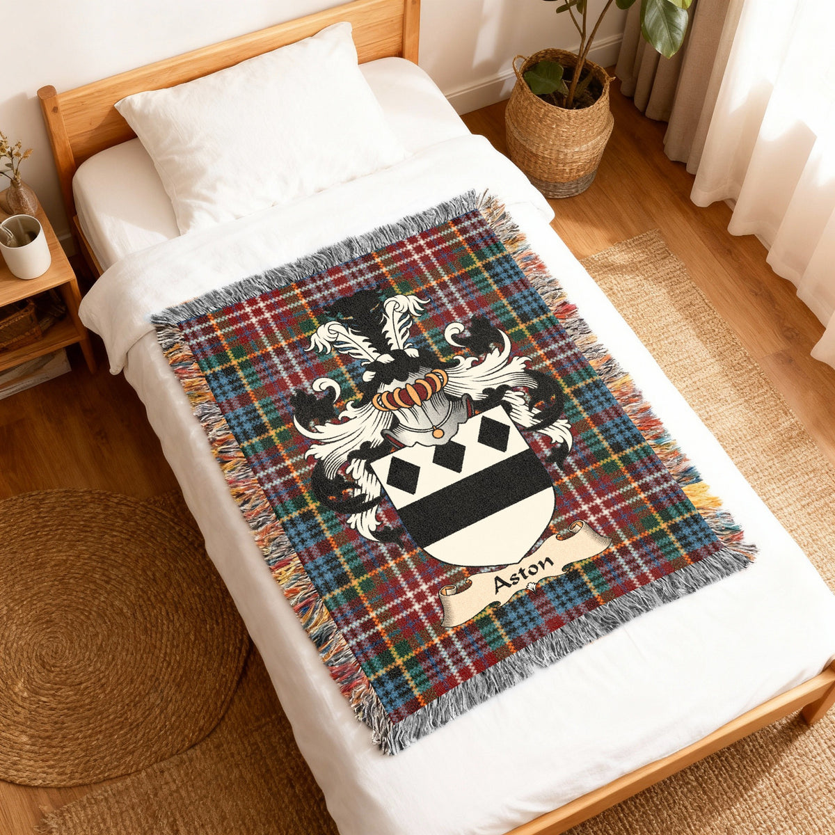 Aston Scottish family shield woven blanket with Caledonia tartan background, displayed on a bed