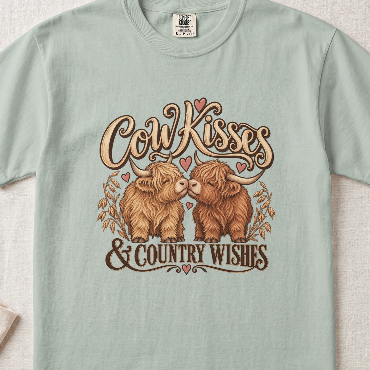 Cow Kisses & Country Wishes Highland cow design on a Bay Comfort Colors 1717 T-shirt, flat lay