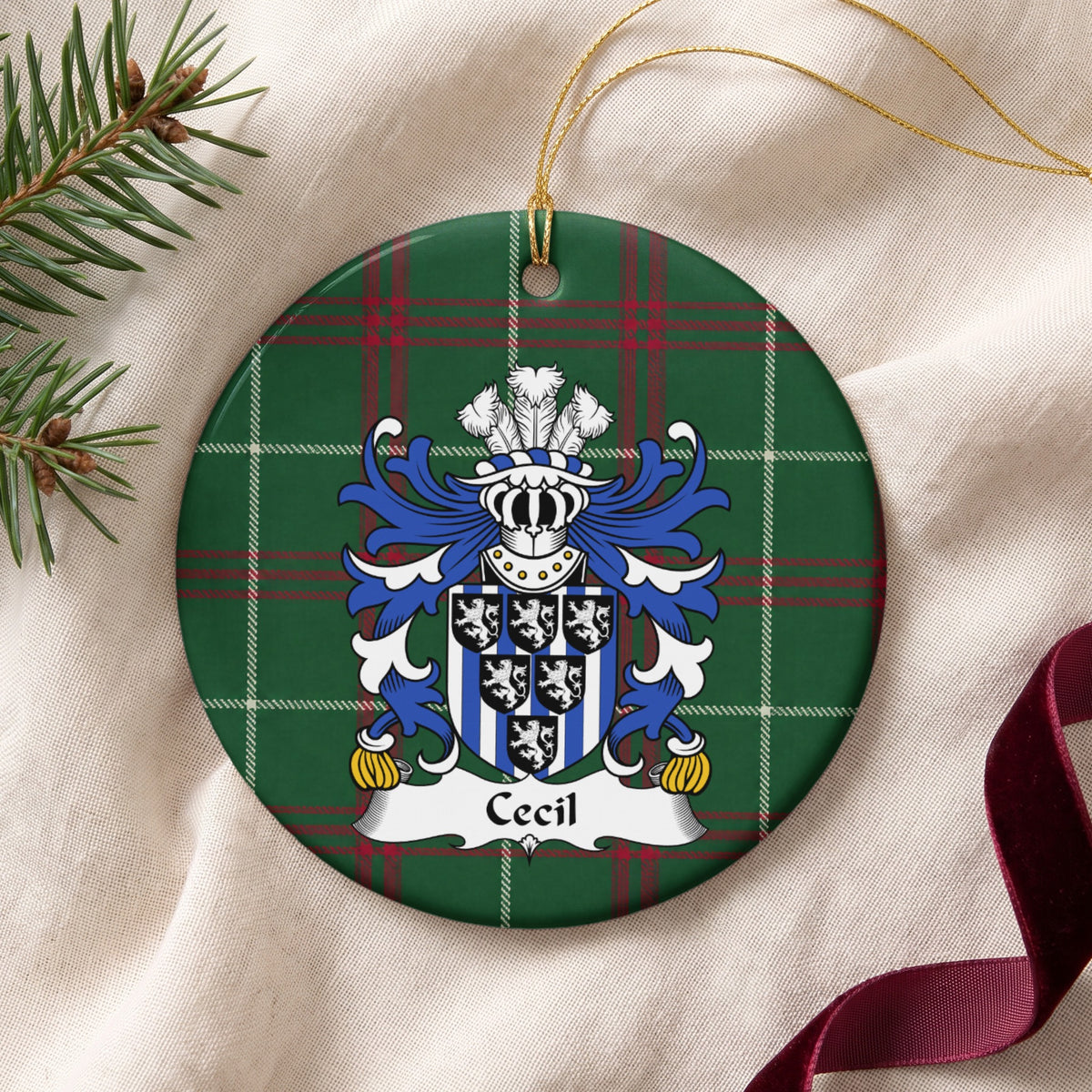 Cecil ornament on cream fabric with gold string, evergreen and burgundy ribbon; six small black shields bearing white lions over blue-and-white vertical stripes on Welsh national tartan.