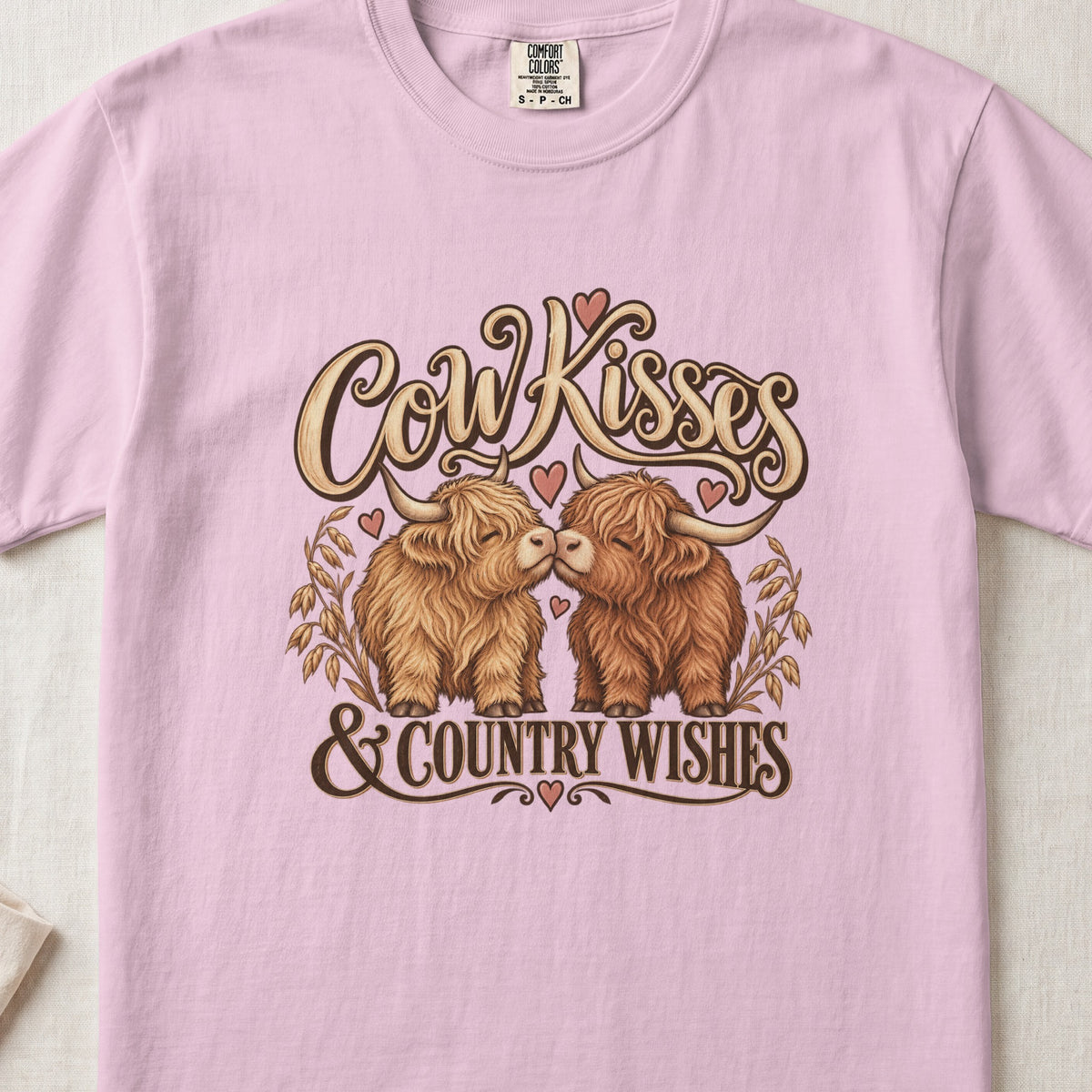 Cow Kisses & Country Wishes Highland cow design on a Blossom Comfort Colors 1717 T-shirt, flat lay