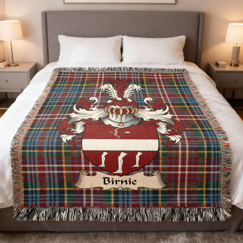 Birnie Scottish family crest woven blanket on a Caledonia tartan background, displayed on a bed