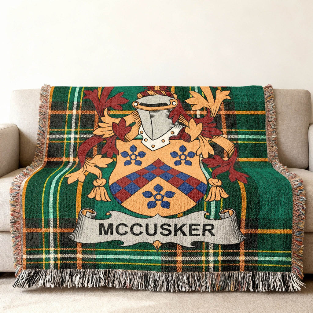 Green tartan blanket with McCUSKER family crest draped on a sofa.