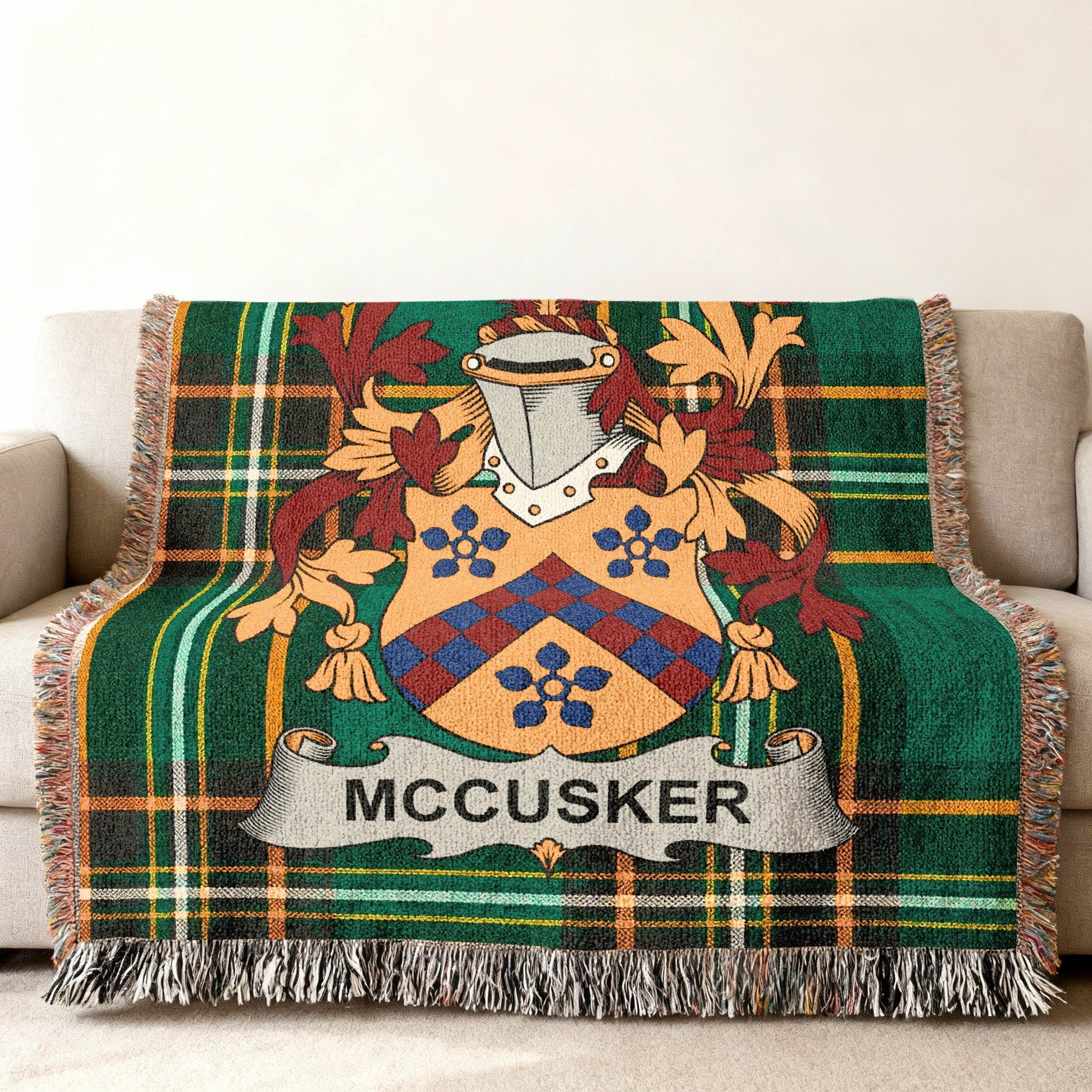 Green tartan blanket with McCUSKER family crest draped on a sofa.