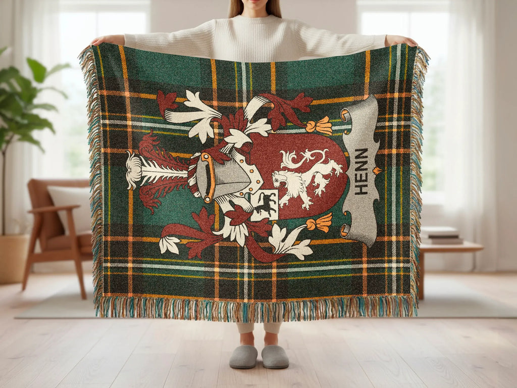 Tartan blanket with crest displaying H ###, held up by a person.