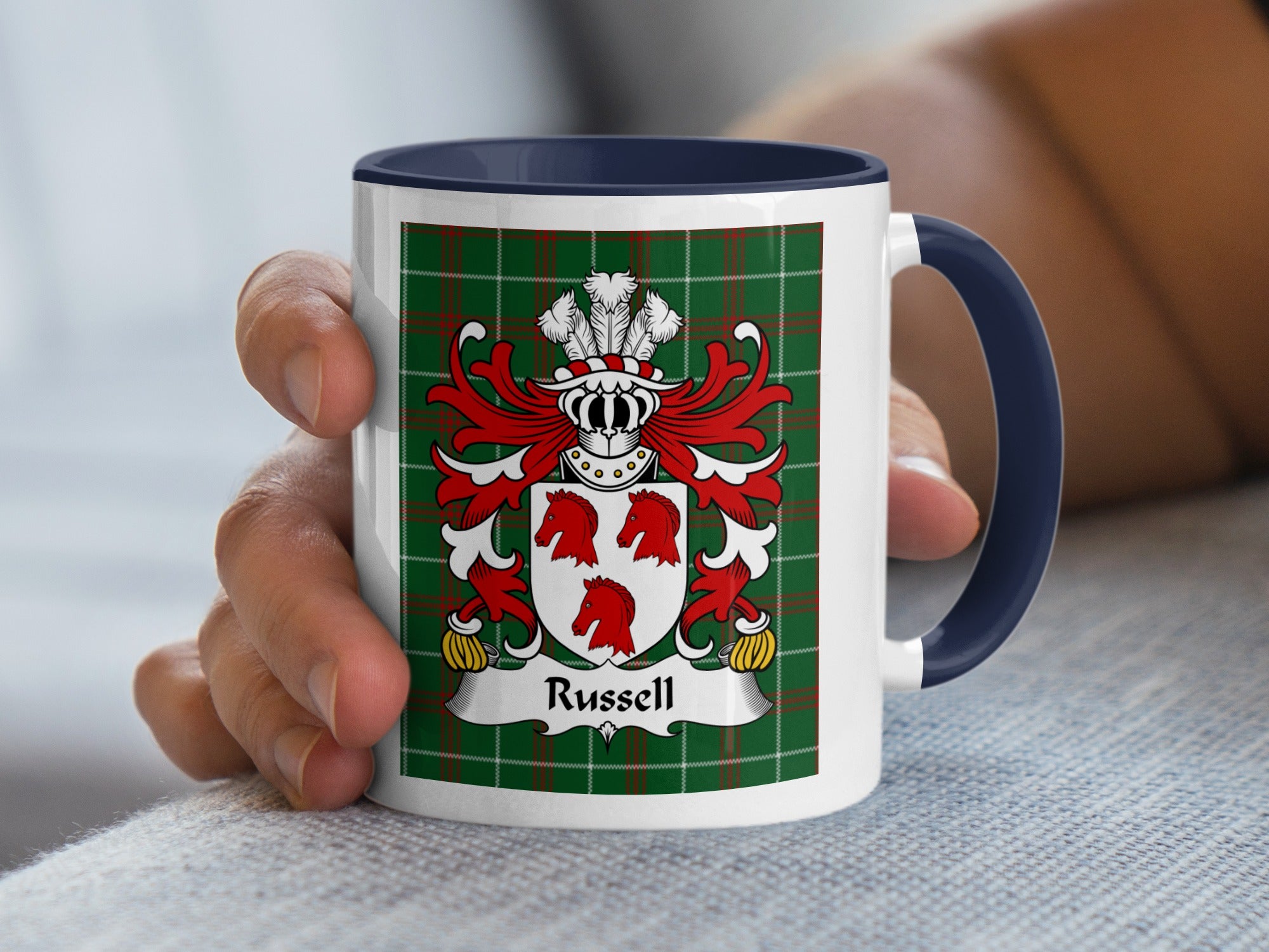 Mug with Russell family crest on green tartan background held by a hand.