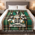 Tartan blanket with "WYRALL" crest and family shield, draped on a bed.