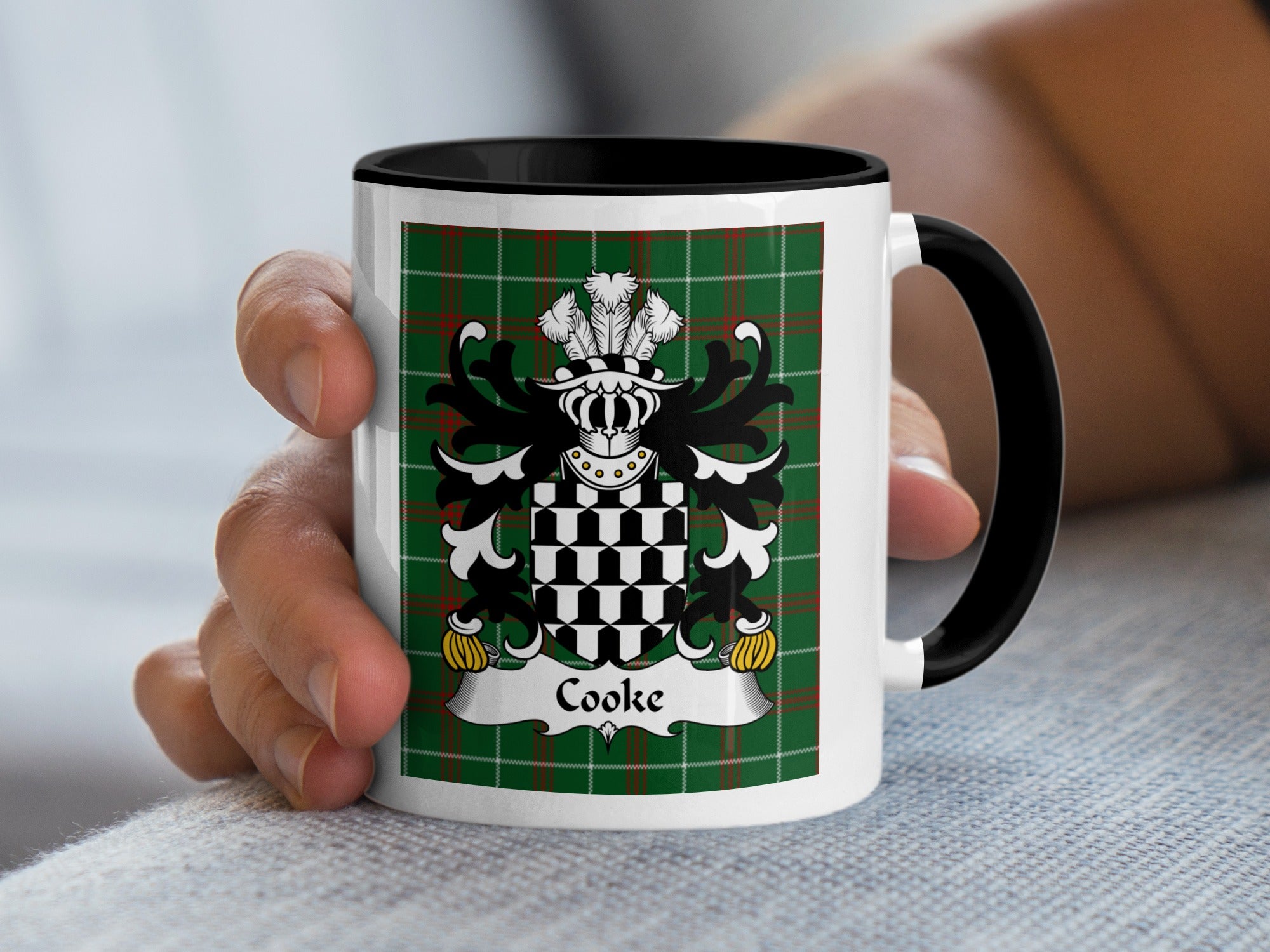 Mug with Cooke family crest on green tartan background held by a hand