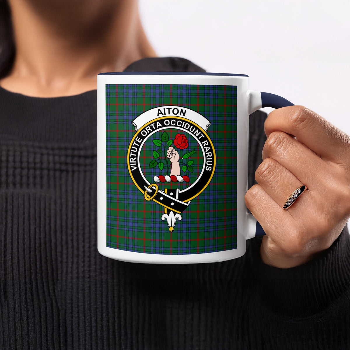 Close-up lifestyle view of Aiton Scottish family crest artwork on a navy 11 oz accent mug with a tartan background
