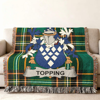 Topping family crest on a green tartan plaid throw blanket with tassels.