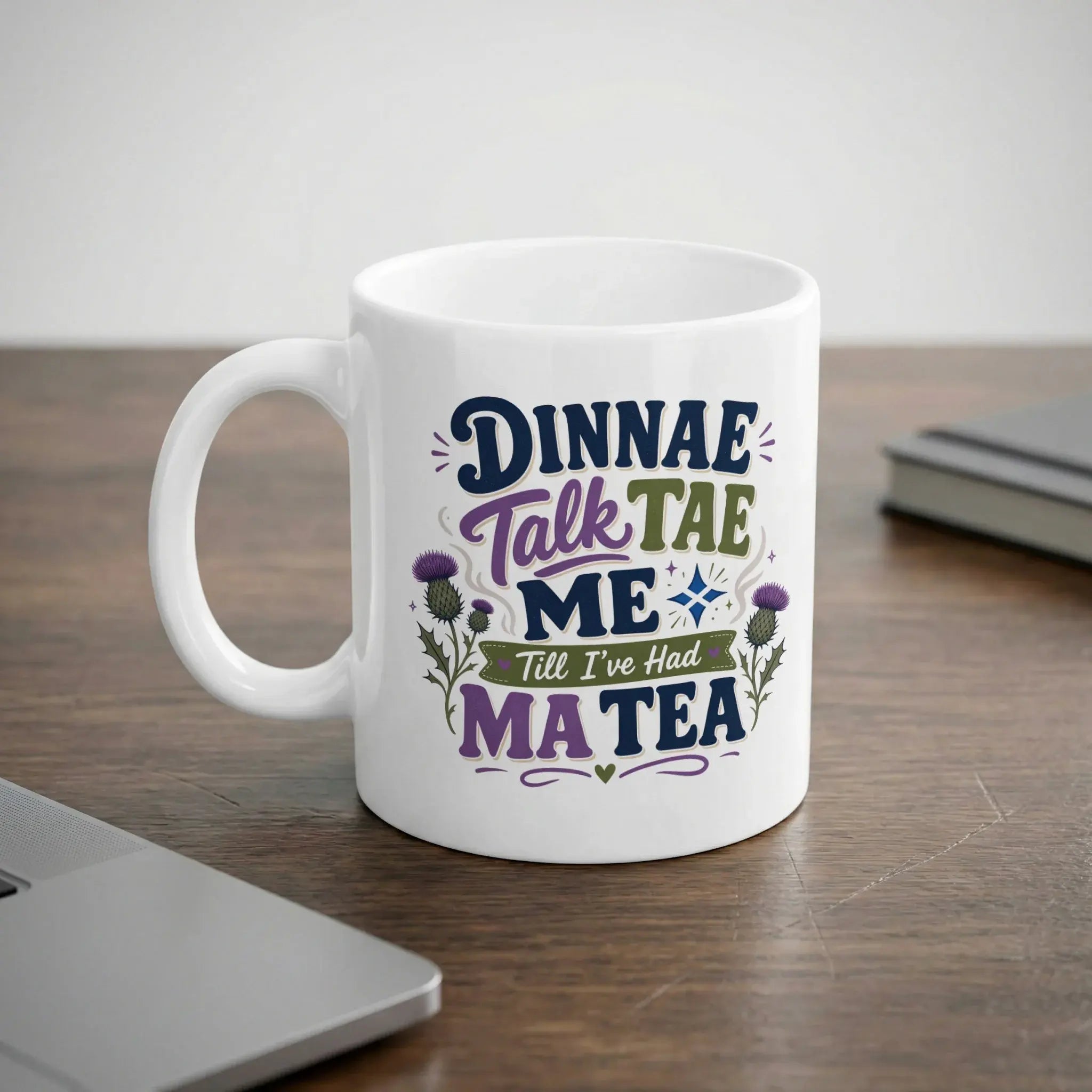 White mug with "Dinnae talk tae me till I've had my tea" text and thistle graphics.