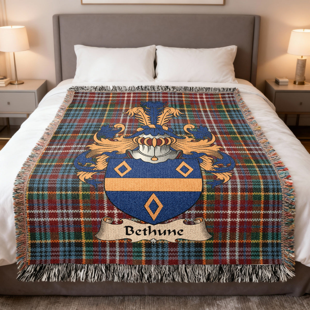 Bethune Scottish family crest woven blanket on a Caledonia tartan background, displayed on a bed