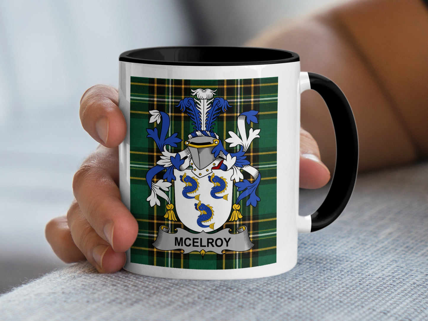 White mug with black rim featuring the McElroy family crest on a green plaid background.