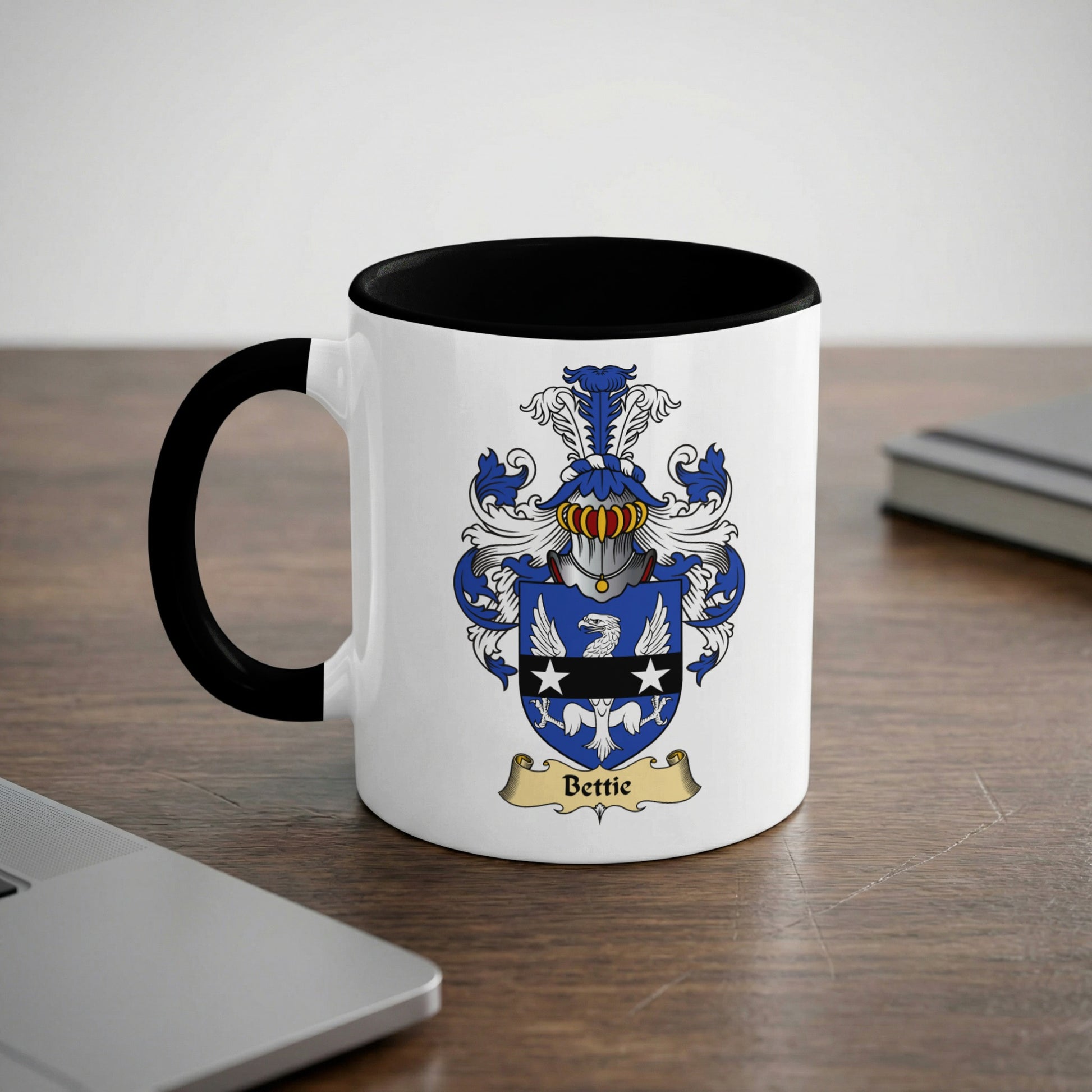 White mug with black rim and handle, featuring a blue and silver coat of arms with the name "Bettie."