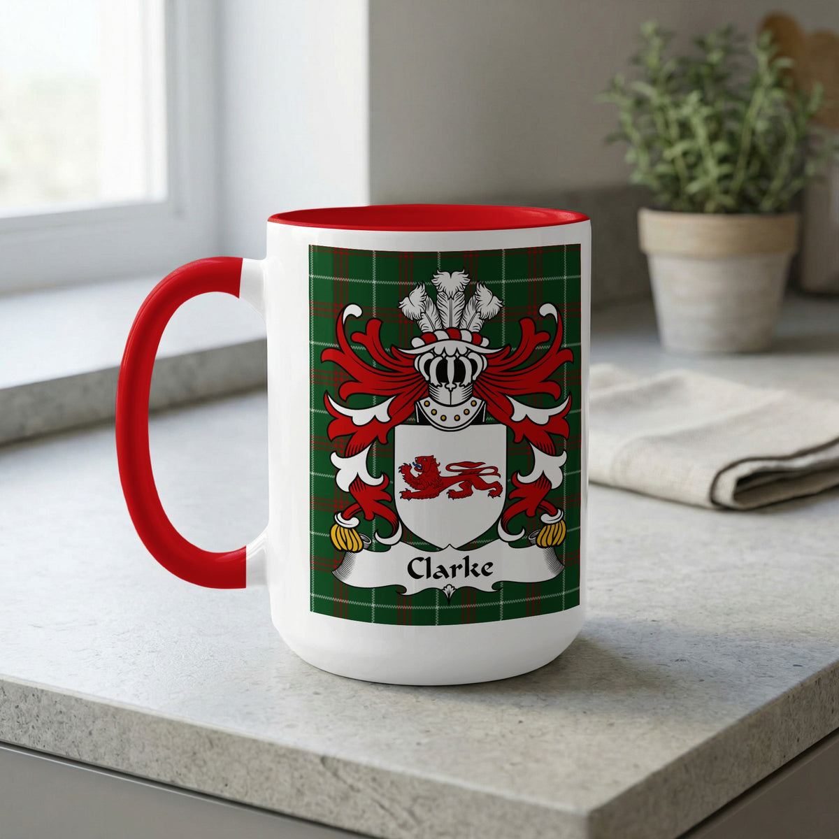 White mug with red handle, featuring the Clarke family crest on a tartan background.