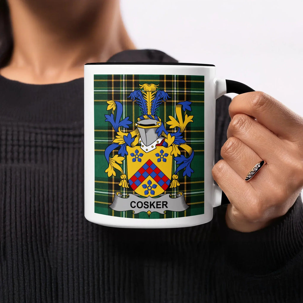 Cosker family crest on a white mug held by a person.