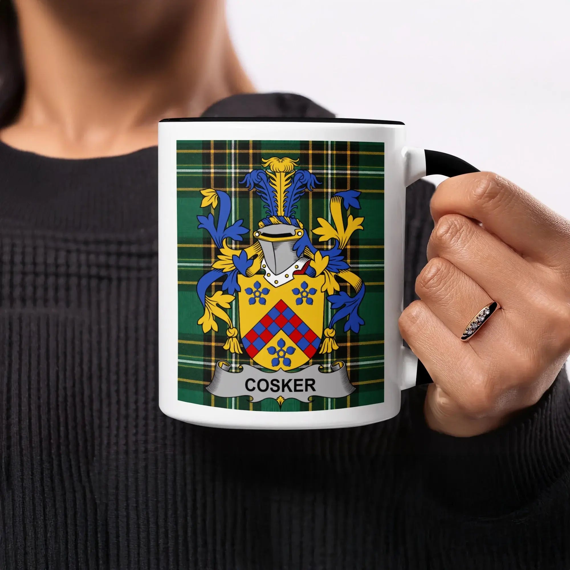 Cosker family crest on a white mug held by a person.