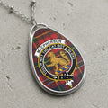 Macpherson clan crest with lion and motto on tartan background, silver necklace.