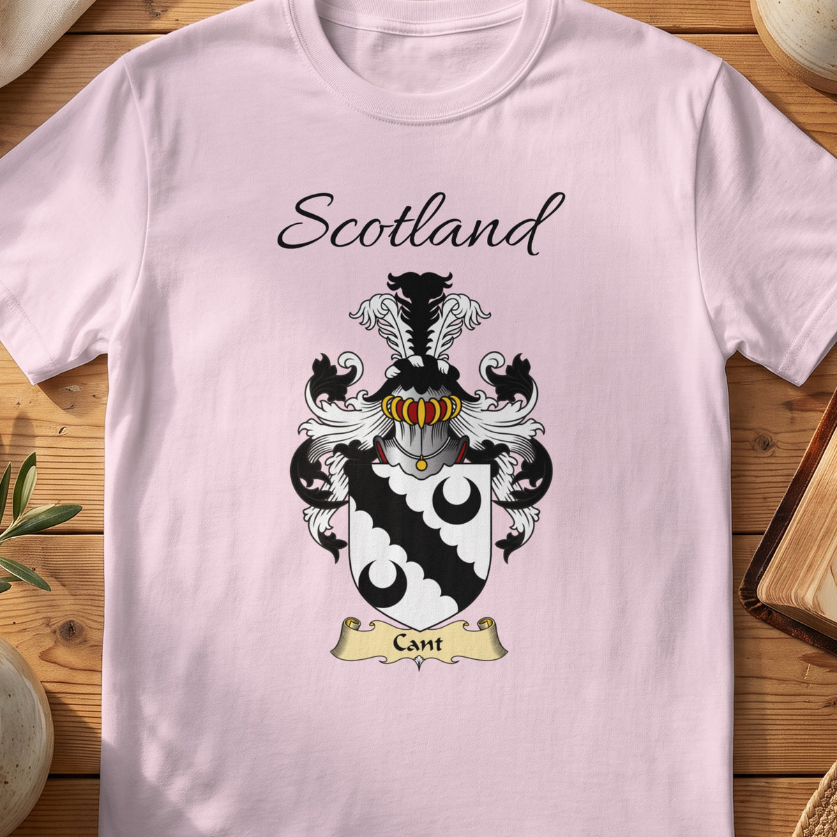Light Pink Cant Scottish family shield T-shirt featuring a black scalloped diagonal band between black crescents